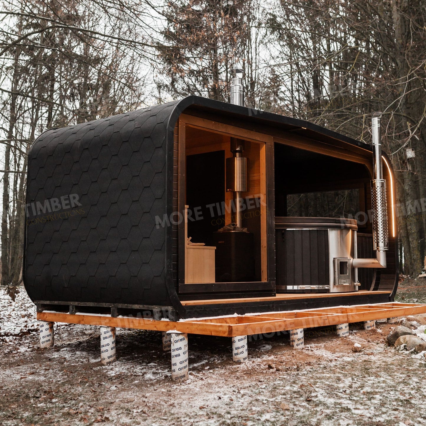 Wooden sauna cabin next to steaming hot tub