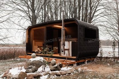 teaming hot tub beside glowing sauna at sunset