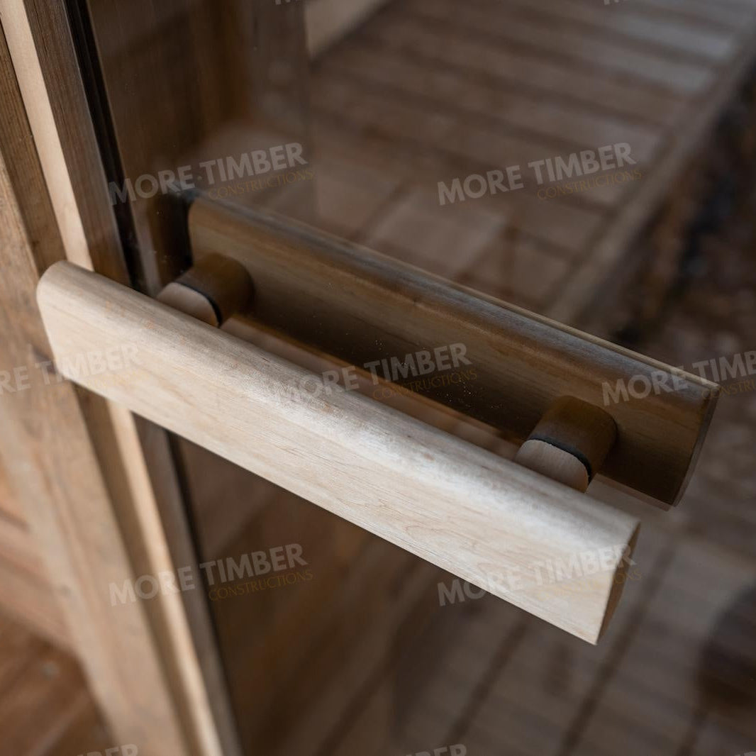 Wooden sauna with 'More Timber' branding, featuring wooden benches and a door.